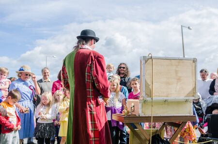 london, england, 15/03/2019 A flea circus street performer with a magnifying glass entertaining children on the city streets. Traditional flea circus ringmaster funny man.のeditorial素材