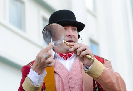 london, england, 15/03/2019 A flea circus street performer with a magnifying glass entertaining children on the city streets. Traditional flea circus ringmaster funny man.のeditorial素材
