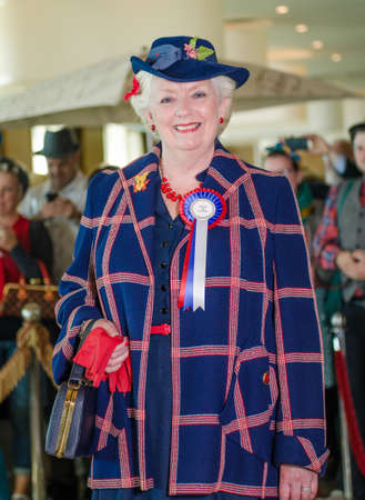 morecambe, England, 05/05/2017, A woman with a beautiful retro style vintage hairstyle and clothing, with a rosette badge,  fashionable women acting and posing in fancy dress cosplay.のeditorial素材