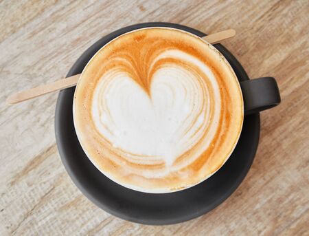 A beautiful creamy brown warm fresh cappuccino coffee cup, full of creamy coffee, served in a wooden...