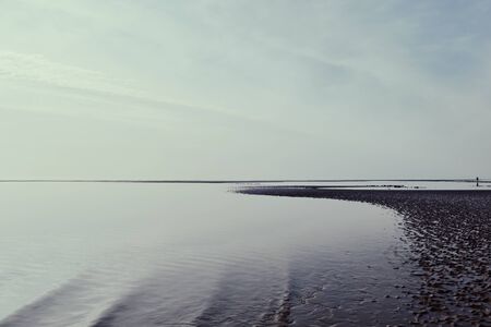 relaxing and gentle calming waves flowing into a beach on an gloomy sunny but overcast day. low...