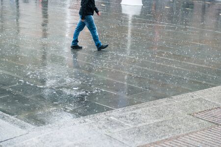 A heavy downpour of rain in an urban city setting, perfect for mock ups and compositing. Rain drops and storms in the city. Rain splashing on the drenched  concrete floor.の写真素材