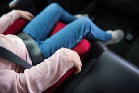 A close up of a child infants hand holding tightly on a seat belt tightly fixed in place, for security and protection of toddlers travelling in a car. Child protection in automobiles and baby booster seats.の写真素材