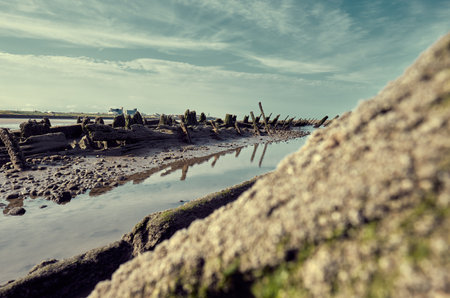 An old historic wooden shipwreck vessel carcass exposed on a desolate tropical island beach....