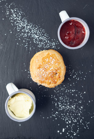 A beautiful gourmet scone served with tea and coffee, strawberry jam and clotted cream. traditional british food. Cackes and see treatsの写真素材