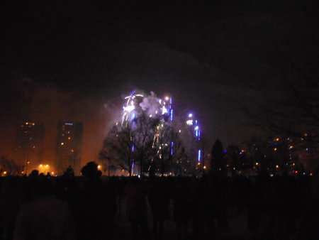 Blue and yellow fireworks initating the New Year pyrotechnics show in the middle of city, emitting smoke and dust.の写真素材