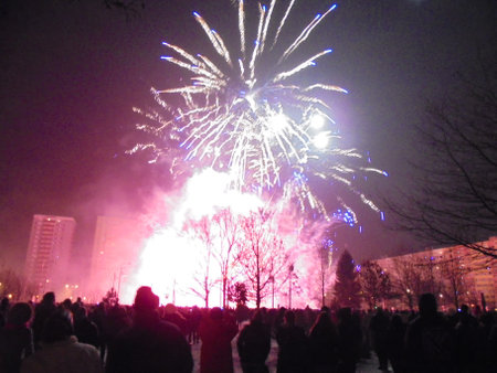 Red and yellow fireworks exploding over crowds during New Year pyrotechnics show.の写真素材