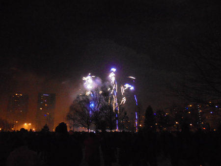 New Year midnight pyrotechnics show start by shooting blue and yellow fireworks in a cloud of smoke covering the city buildings.の写真素材