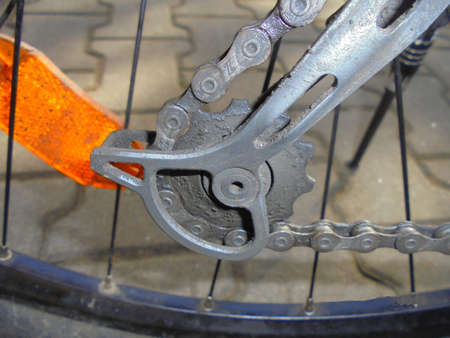 Bottom gear of mountain bike derailleur with chain and orange reflector in the background.の写真素材