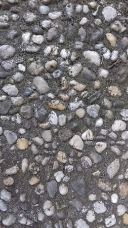 Image of small pebbles and rocks embedded into hard concrete suitable as background.の写真素材
