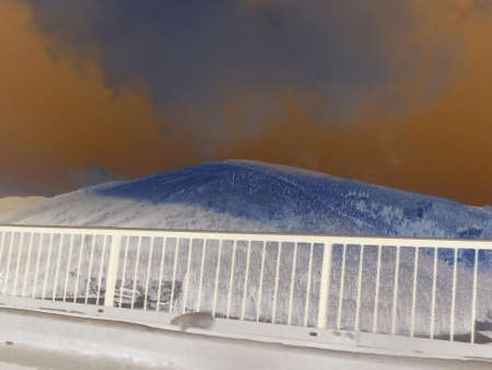 Inverted image - Winter mountain scene: Cupel hill in Beskydy, Czech, with spruce forests covered in snow with sparse mist cloud on the bright sky.の写真素材