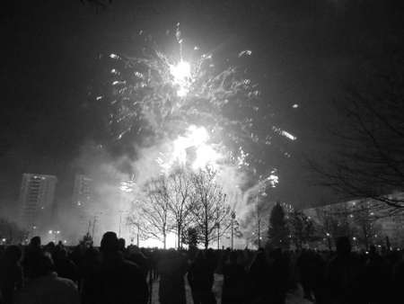 Blackwhite image - Smoking effect of white fireworks during New Year pyrotechnics show flashing on buildings and people.の写真素材