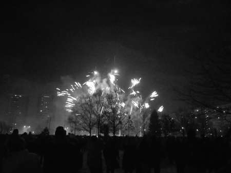 Greyscaled image - Final light explosion of first wave of blue fireworks during New Year midnight pyrotechnics show.の写真素材