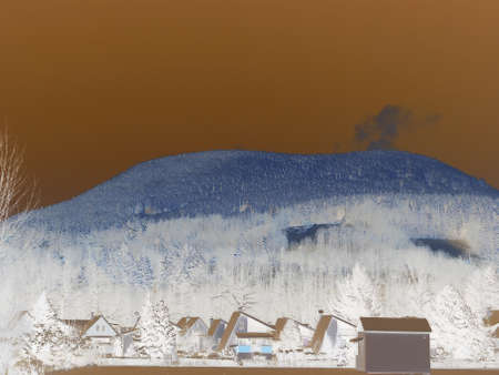 Negative image - Majestic mountain scene, Czech hill Ostra Hora in Beskydy and its dense spruce forest coated in snow, towering over several small village houses.の写真素材