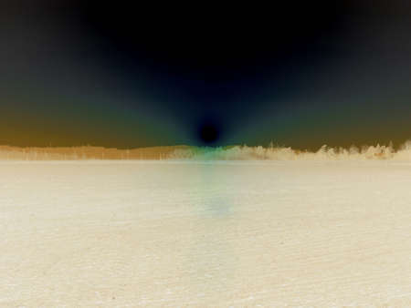 Inverted image - Majestic slightly overexposed image of setting sun creating massive light on the sky over the bare field and mountains in the distance.の写真素材