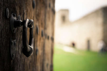 Old wooden door with door knocker and castle in the backgroundの写真素材