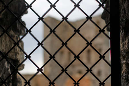 Old iron bars in window with view on the castle in backgroundの写真素材