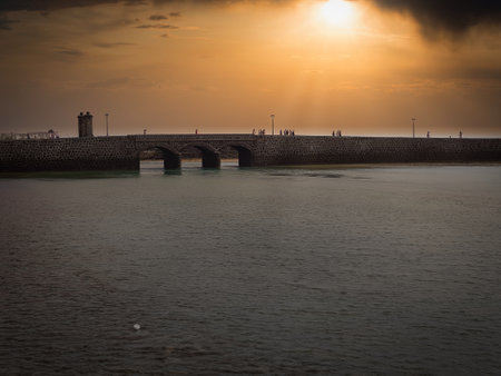 Sunset over the bridge and the breakwater at the seaの写真素材