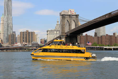 The New York Water Taxi travelling up the Hudson River with the Brooklyn Bridge behindのeditorial素材