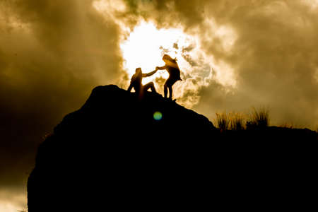 silhouettes on top of a mountain with an epic skyの写真素材