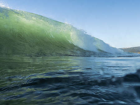 View from the ocean of a large comber wave cresting and breaking as it races towards the shore - surfers viewpointの写真素材