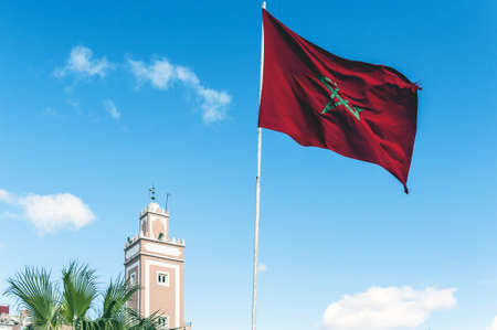 Mosque tower with Morocco flag against the blue sky backgroundの写真素材