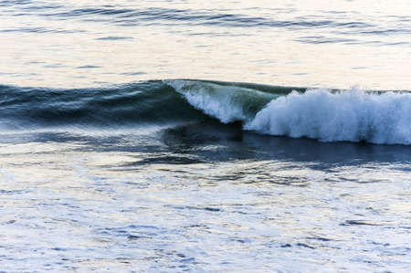 Marine or nautical background of breaking waves rolling in across a calm oceanの写真素材