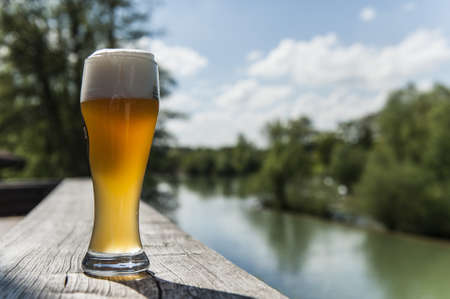 A glass of beer on the terrace near by a lake の写真素材