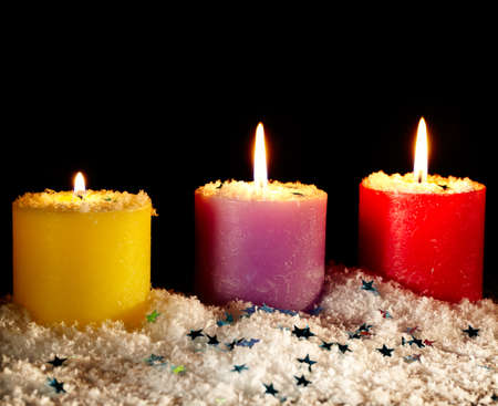 Three festive candles covered with artificial snow on a black background  Frontal view with copyspace の写真素材