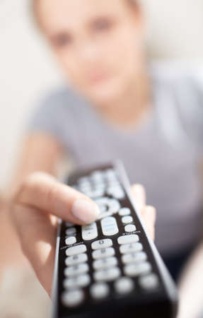 Young woman with remote watching TV  Shallow dof close-up focused on remote control 