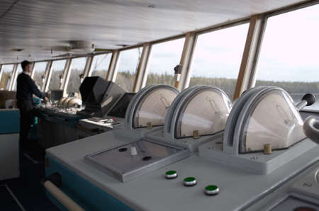 Navigational officer driving the ship on the river. Wide shot.