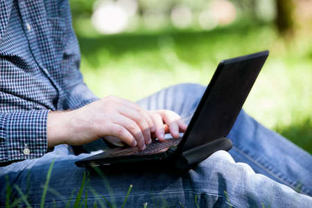 Hands of businessman working with laptop in the park.の写真素材