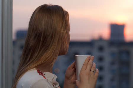 Girl drinking tea in the evening on the balcony.の写真素材