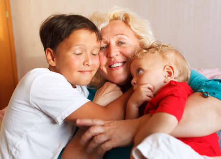 Happy grandmother hugging with her grandchildren at home