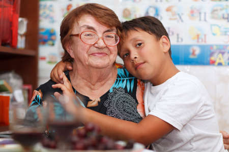 Grandson is hugging his grandmother looking to the camera