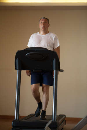 Fit attractive middle-aged man working out on a treadmill in a health and fitness concept