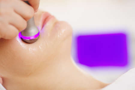 Macro shot of woman under lifting procedure provided by cosmetician with special equipment