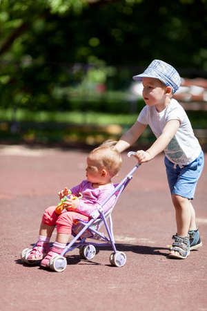 Young boy pushing little sister in a baby strollerの写真素材