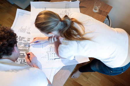 High angle shot of male and female architects at work  Woman pointing on the place on the map