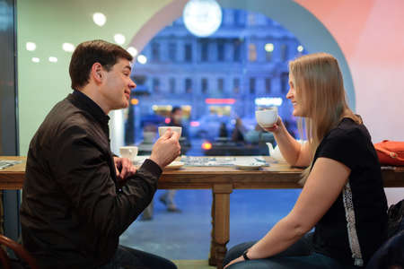 Man and woman chatting over a cup of coffee inside a cafe or restaurantの写真素材