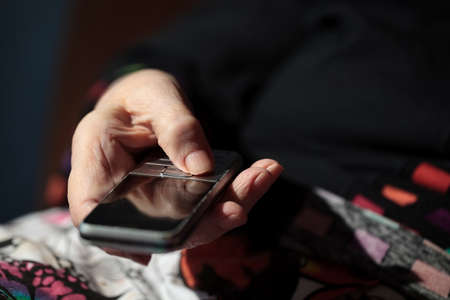 Close-up shot of elderly womans hands holding a cell phone  She is going to dial a numberの写真素材