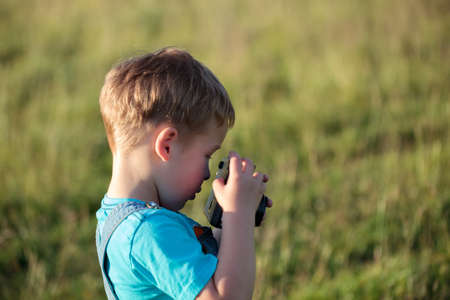 Little boy trying to make photos with camera outdoorの写真素材