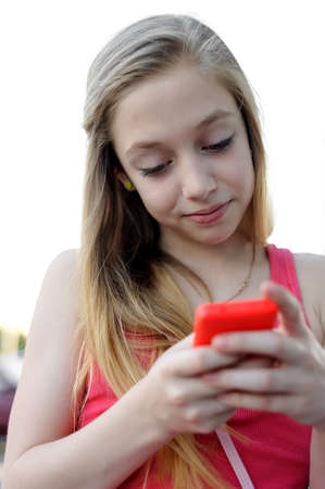 Young girl typing sms on her pink smartphone outdoorの写真素材