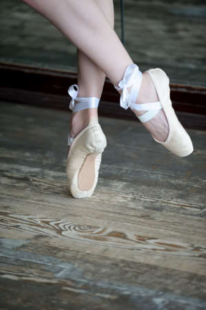 Close-up shot of female feet in ballet shoes dancing on the wooden floorの写真素材