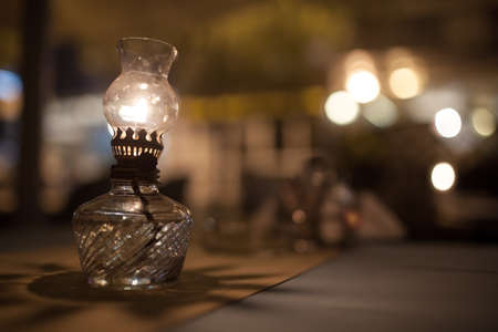 Close-up shot of lit vintage oil lamp standing on the table in a cafe. Warm and cozy atmosphereの写真素材