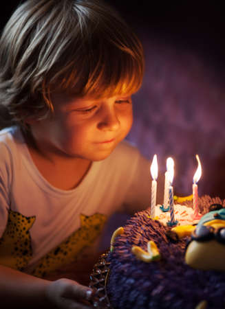 Little boy blows out candles in the cake for his 4th birthdayの写真素材