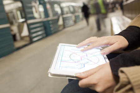 Close-up shot of woman using tablet computer in subway. She looking at underground map on pad...