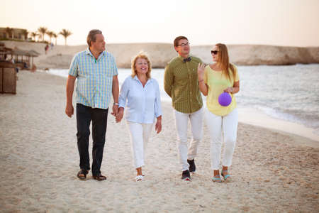 Happy senior and young couples having a walk at the seaside. Parents and adult children together...