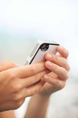 Close up view of the hands of a child checking a text message on a mobile or texting a friendの写真素材