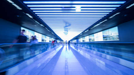 People going in walkway and riding flat escalators at the airport of Seoul, South Korea. Futuristic blue toned shotの写真素材